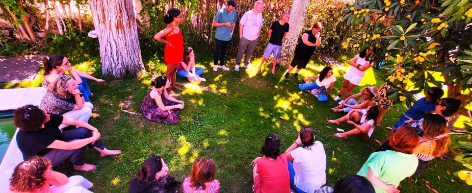 Group of Stone Soup community members sit on the garden floor in a circle and chat