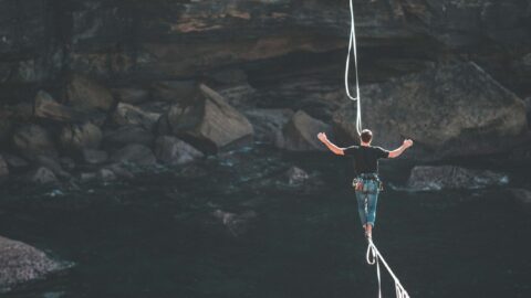 A man walking on a cable over a cliff