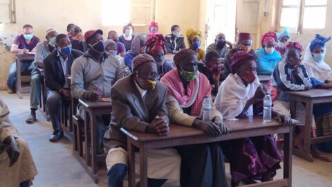 Community members sit in a classroom listening during a meeting