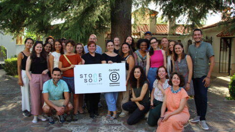 A group of stone soup community members holding the bcorp and stone soup logos